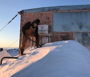 An expeditioner digging snow out away from a field hut