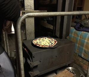 A pizza ready to cook sitting on a wood fired stove