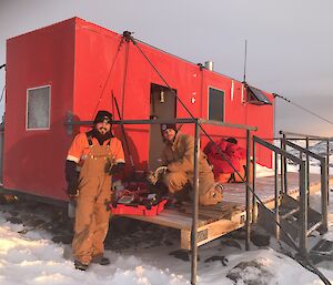 Two expeditioners test and tag the electrical equipment at a field hut
