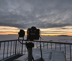Camera on a tripod pointing at the sunset over the horizon