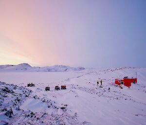 Cool evening light casts a pastel glow over the red watts hut and five quad bikes