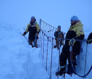 three expeditioners clearing the bridge of snow