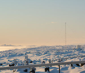 Fog and wintery light shroud the islands in the background while the met instrument enclosure in the foreground is covered in snow