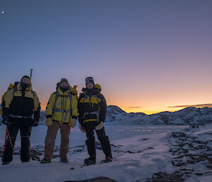 Three lads standing for a photo with a cool sunrise and frozen Ellis Fjord behind them