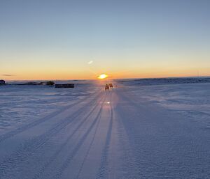 Expeditioners on quads onto the sea ice to drill as the sun rises near Casey