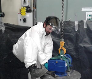 Plumber dressed in white coveralls completes a messy plumbing task in a workshop