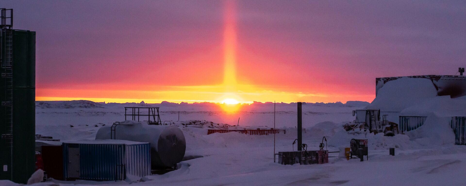 An orange solar pillar lights up the purple horizon during the last sunset for six weeks