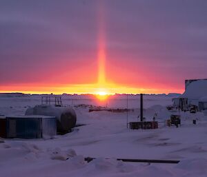 An orange solar pillar lights up the purple horizon during the last sunset for six weeks