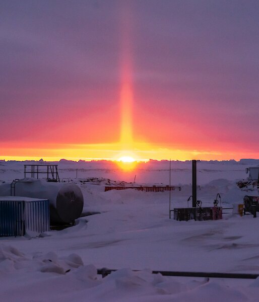 An orange solar pillar lights up the purple horizon during the last sunset for six weeks
