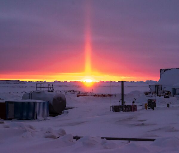 An orange solar pillar lights up the purple horizon during the last sunset for six weeks