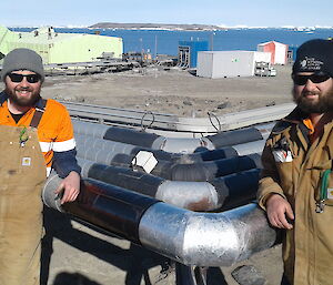 Two plumbers lean against site services pipes