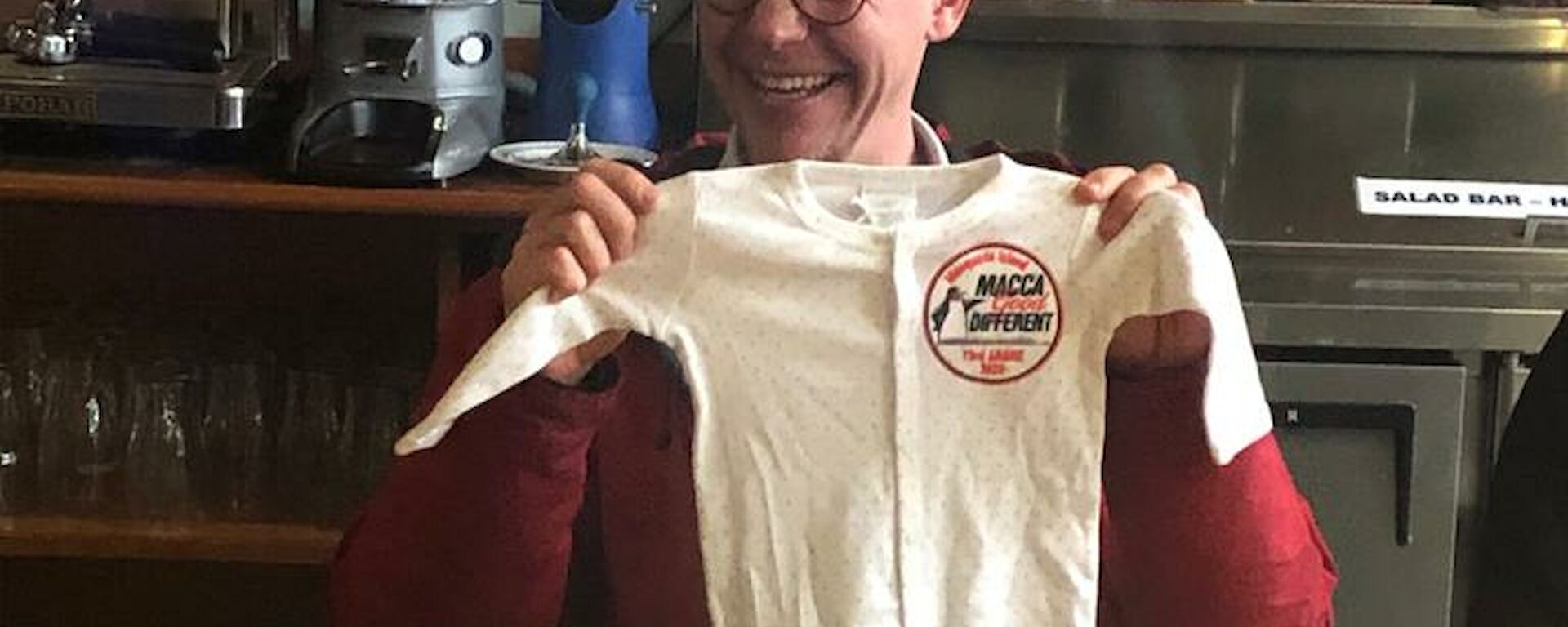 Expeditioner holding a baby onesie at the table.