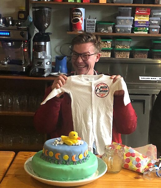 Expeditioner holding a baby onesie at the table.