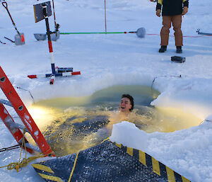 Davis station electrician, Peter Boyle, laying back in a sea ice swimming pool for his midwinter dip.