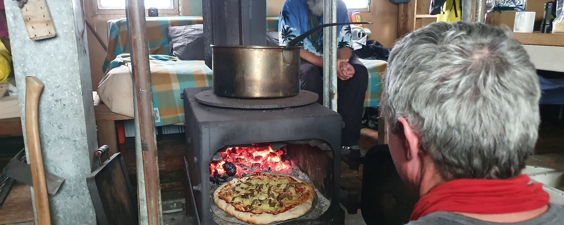 a pizza cooking in the oven at a field hut