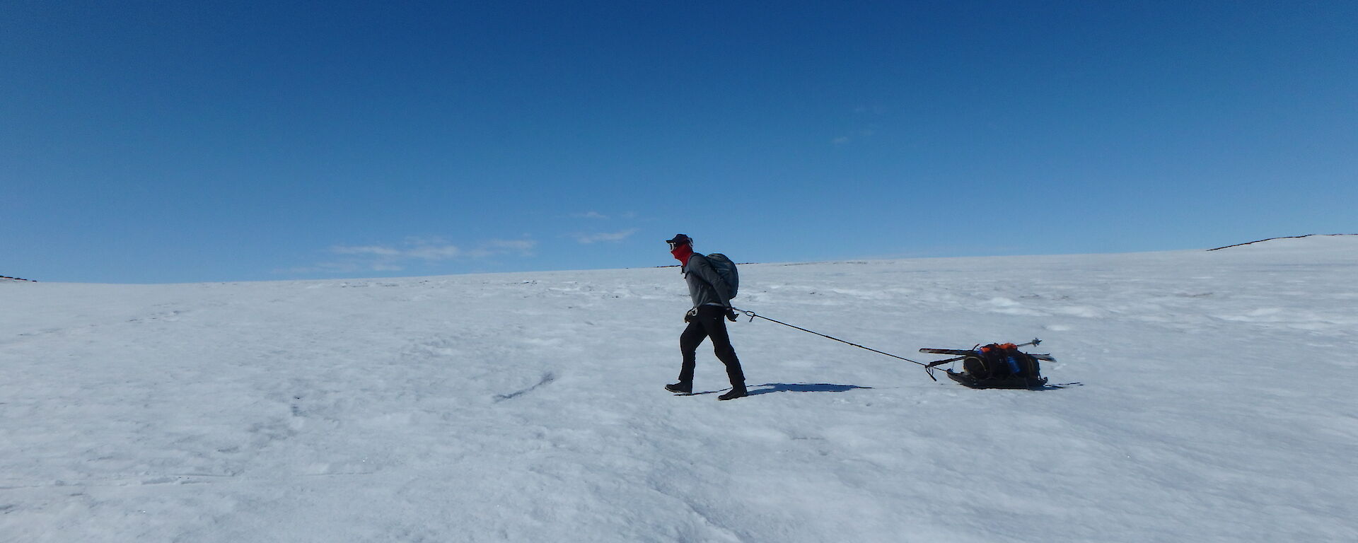 An expeditioner man-hauling his pack on the ice