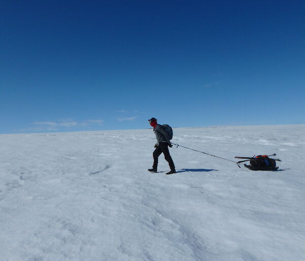 An expeditioner man-hauling his pack on the ice