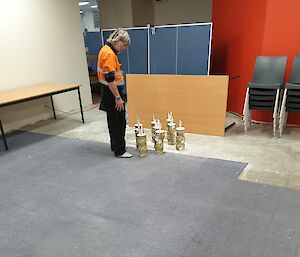 Man setting up skittles made from spatulas and toilet paper for the Midwinter Games.