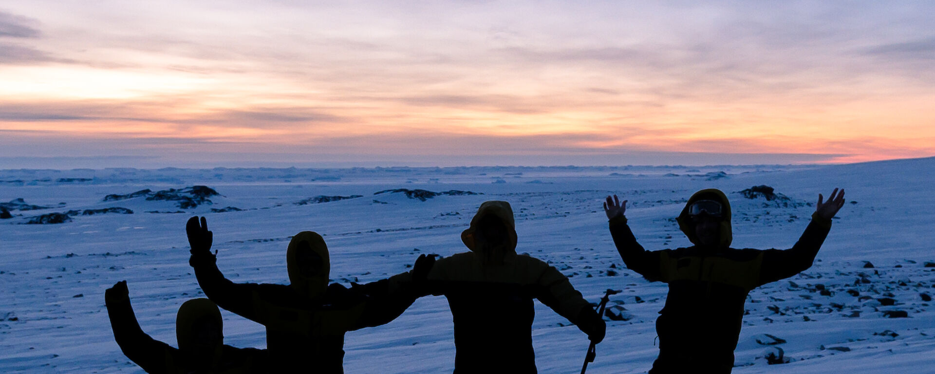 Photo of a group silhouetted up on a rocky outcrop