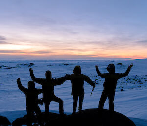 Photo of a group silhouetted up on a rocky outcrop