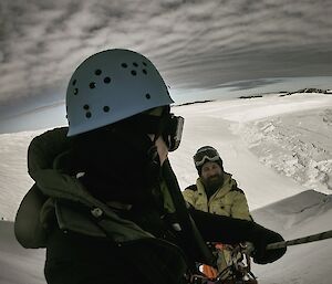 Two expeditioners on an ice cliff
