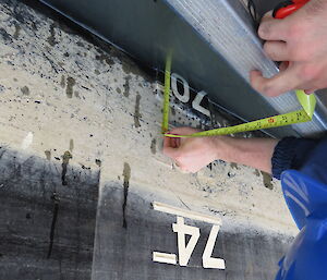 Using a tape measure to measure the height of the ship above the waterline.