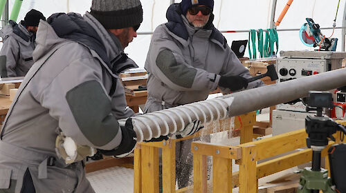 Two men removing an ice core from a drill barrel