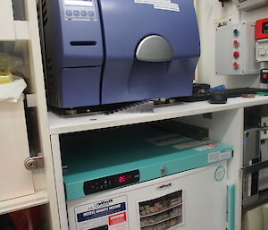 A small blue autoclave to sterilise instruments and a fridge for medicines and vaccines.