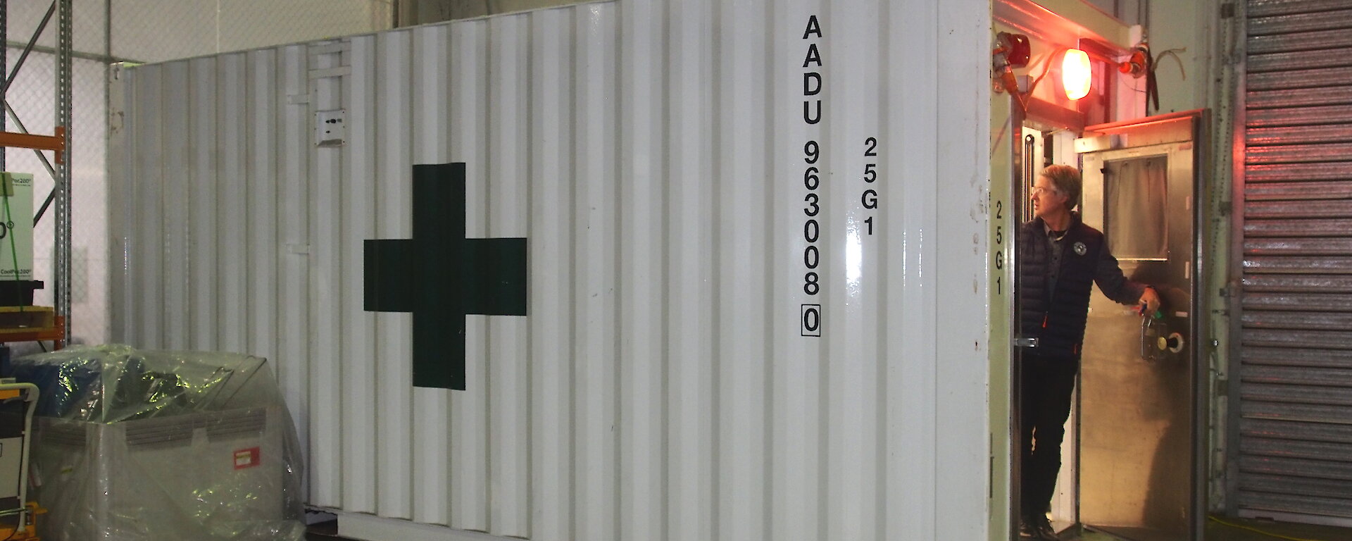 A white shipping container with a green cross on the side.