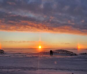 Sun dogs, or an atmospheric optical phenomenon that consists of a bright spot to one or both sides of the Sun on the horizon