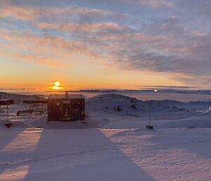 The blazing sun setting over distant icebergs