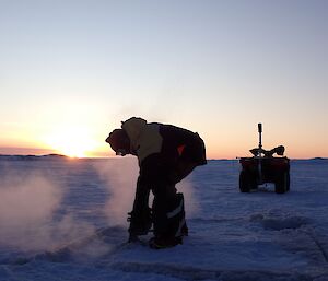 An expeditioner (Duncan Logan) at Casey uses a chainsaw to cut a hole in the sea ice near the wharf to use for the traditional Midwinter swim