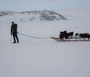 An expeditioner pulling an old school sled across the sea ice