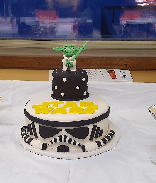A Starwars themed cake is flanked on the dessert table by churros on one side and chocolate mousse on the other
