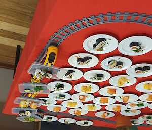 The yellow sushi train, stacked with sushi plates circling a red table full of many more sushi plates