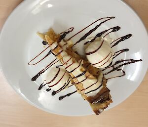 A piece of cake with ice cream and chocolate sauce