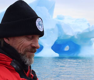 An expeditioner in front of an iceberg in the water