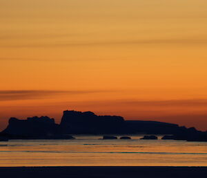 Silhouette of an iceberg in the distance at sunset