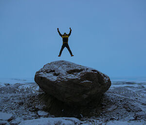An expeditioner jumping on top of a rock