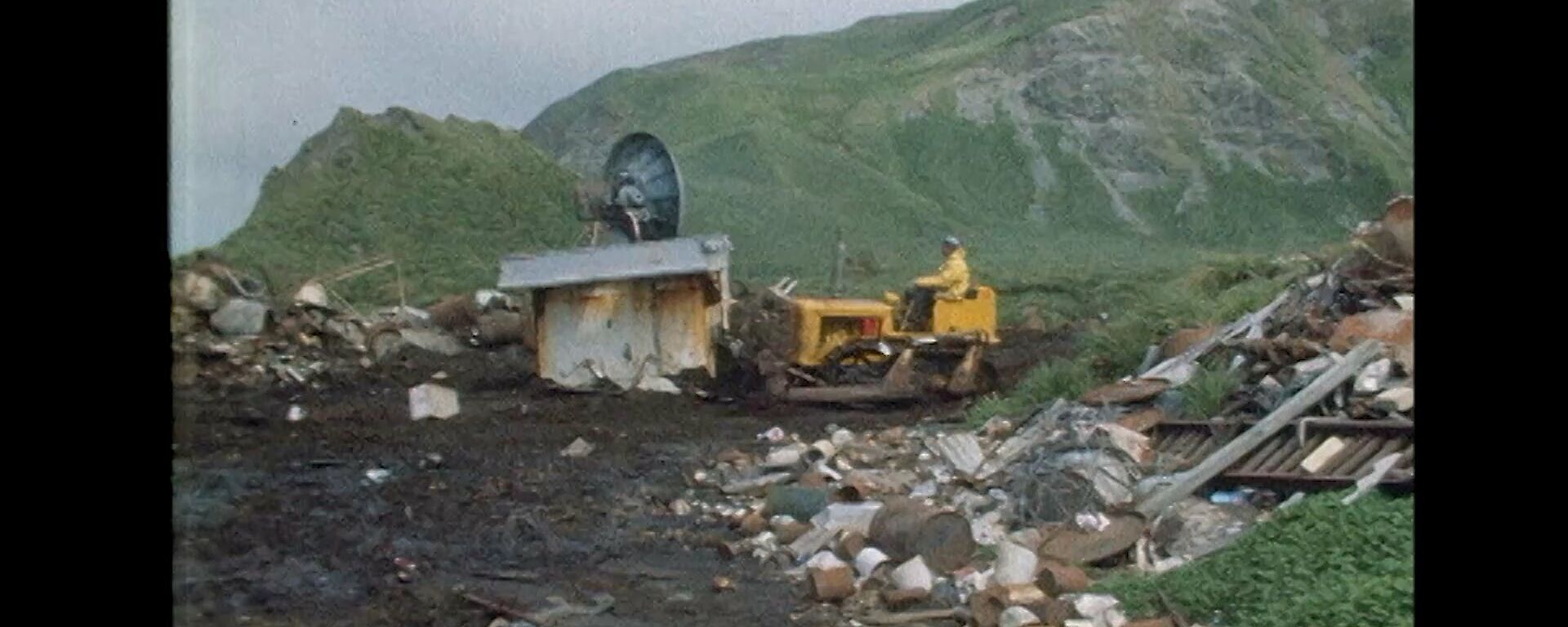 Heavy machinery breaking down an old Macquarie Island hut at the site of the old waste dump