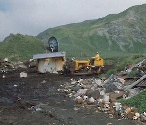 Heavy machinery breaking down an old Macquarie Island hut at the site of the old waste dump