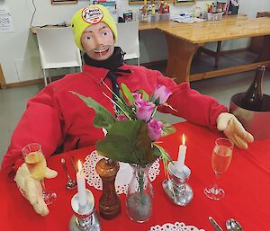 A CPR dummy sits at a table