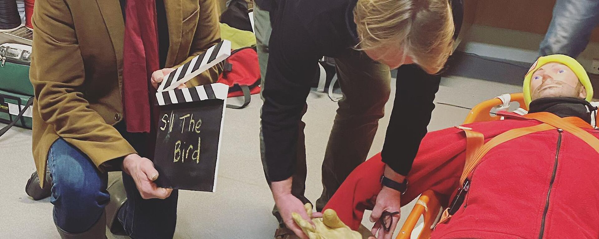 Two expeditioners prepare a scene with a CPR dummy for filming a video