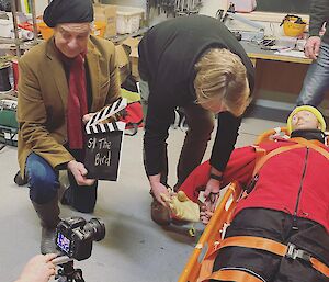 Two expeditioners prepare a scene with a CPR dummy for filming a video