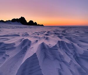 Icy landscape with mountains on the horizon with neon sky and purple snow