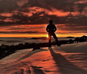 An exepeditioner standing on the ice looking at a Ruby Sunset