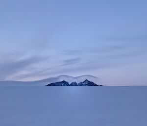 Portrait of a mountain in the distance with an interesting cloud over it