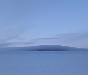 Portrait of a mountain in the distance with a cloud enveloping it