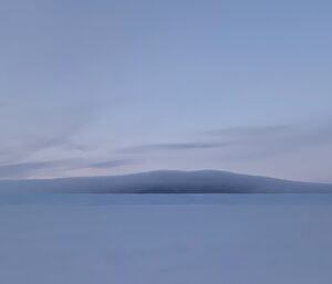 Portrait of a mountain in the distance with a cloud enveloping it