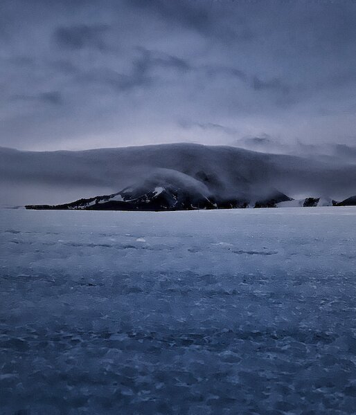 Portrait of a mountain in the distance with a cloud enveloping it
